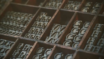 Multiple copies of movable type letters in a wooden frame