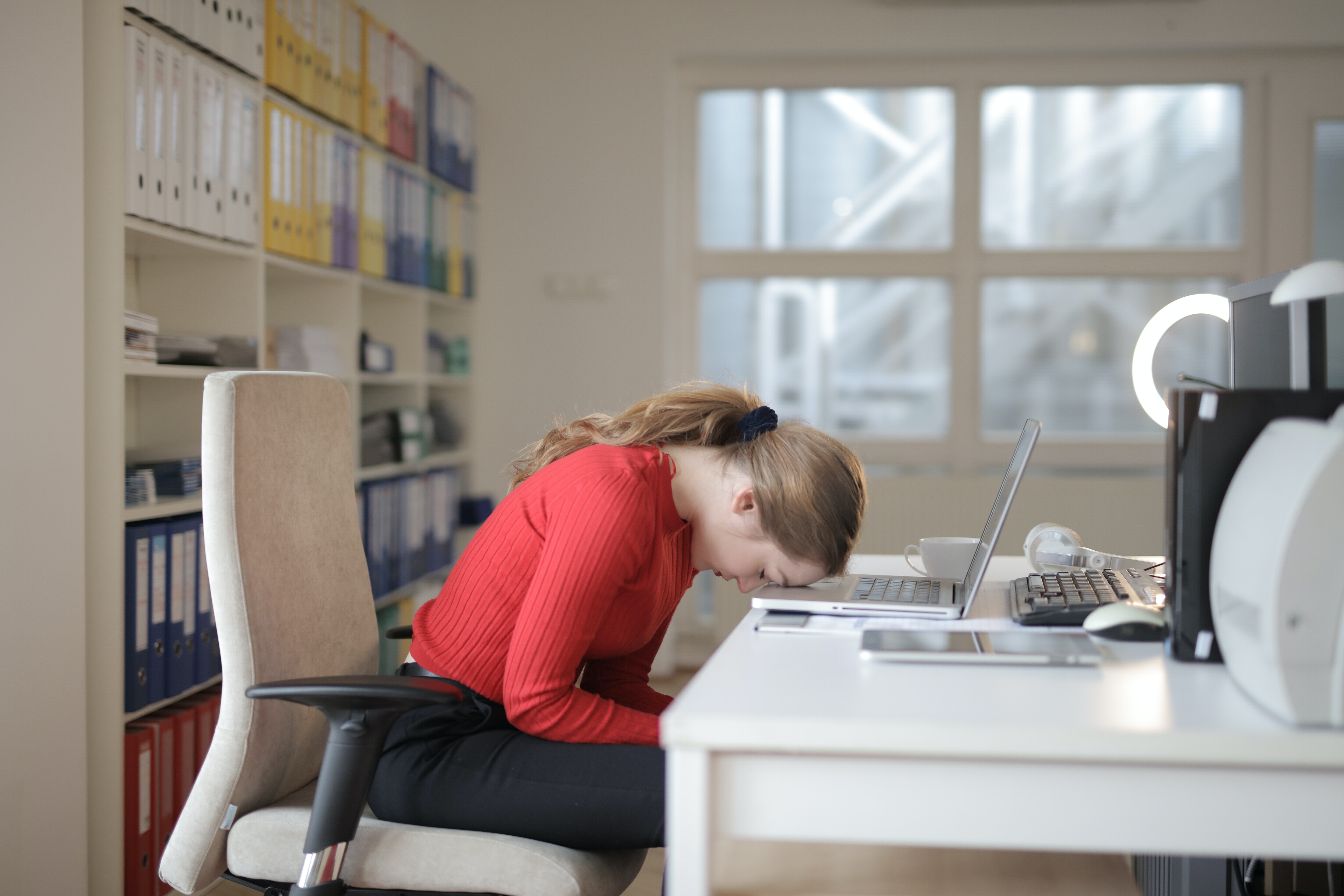 Woman asleep on top of laptop on a desk