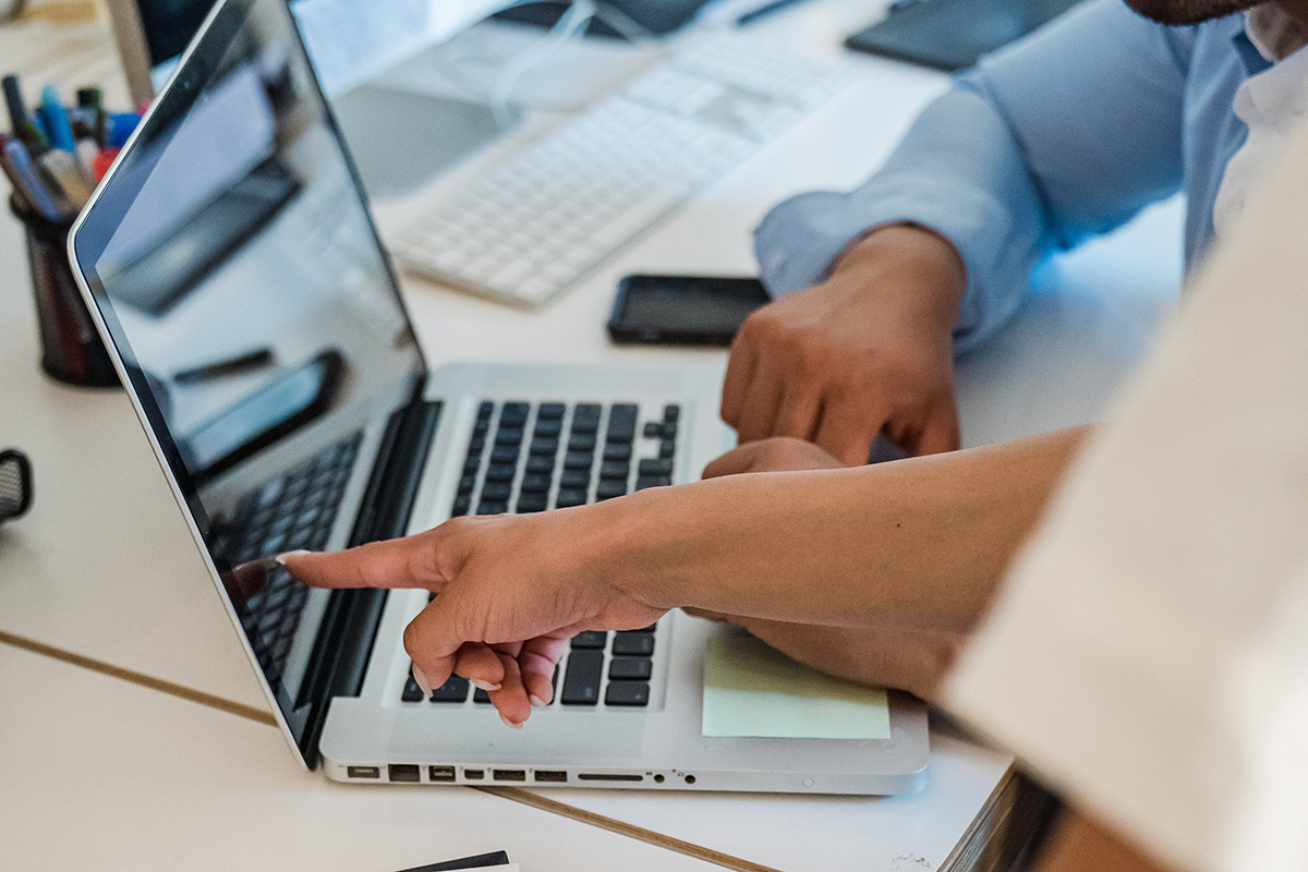 A finger pointing demandingly at a laptop screen